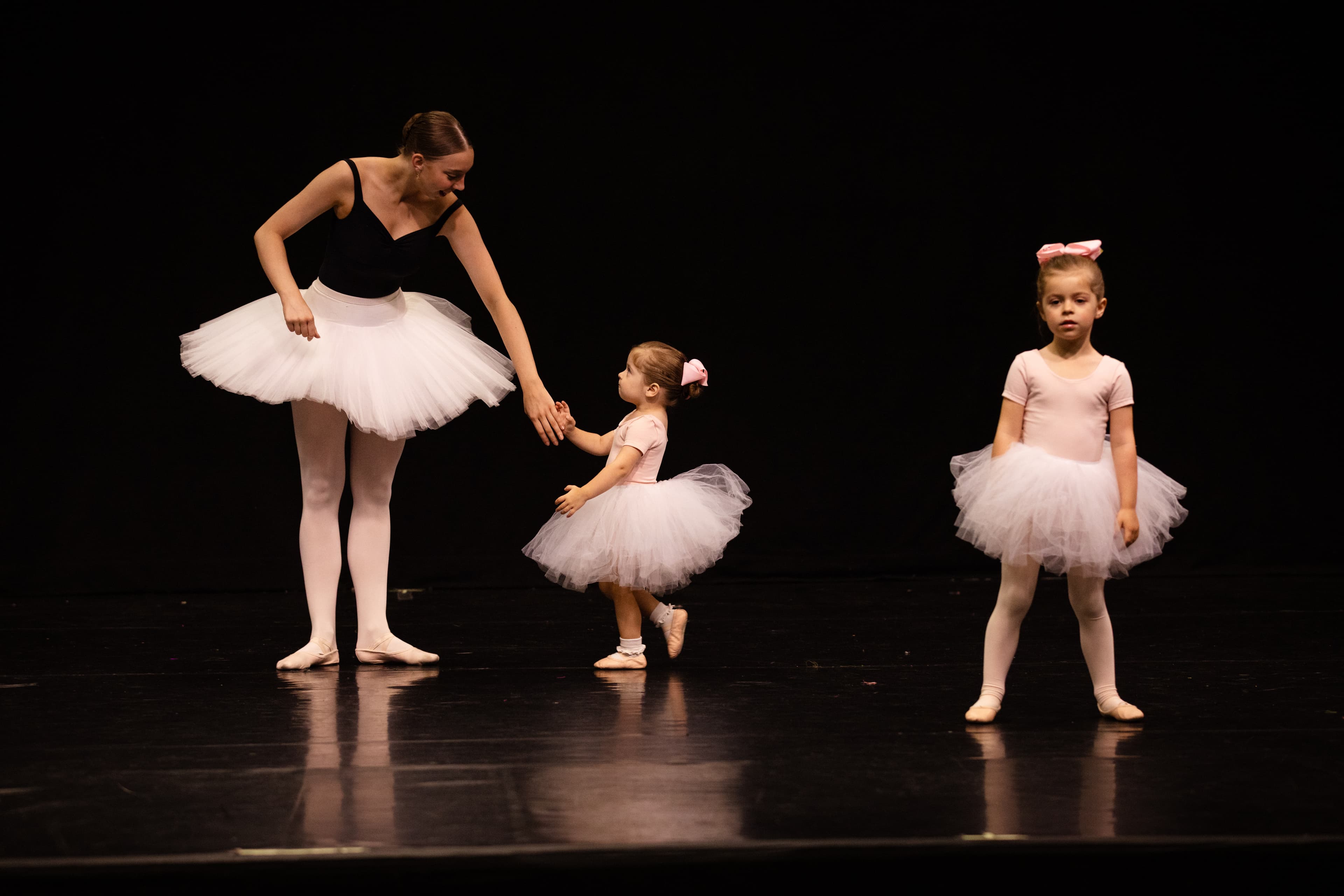 Teacher guiding a little dancer on stage