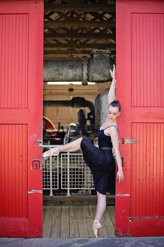 Ballerina in arabesque at red doors