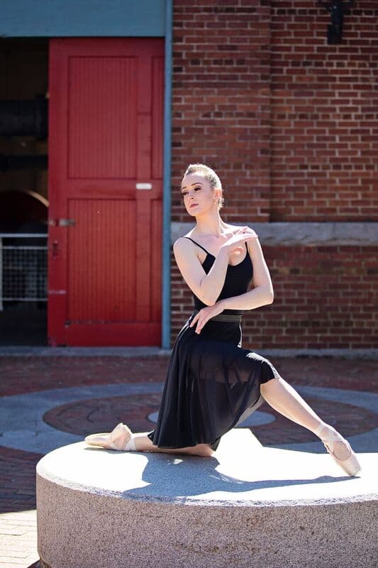 Ballerina seated on an outdoor pedestal