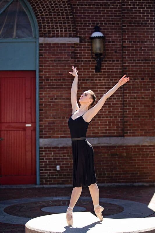 Ballerina with arms raised outdoors